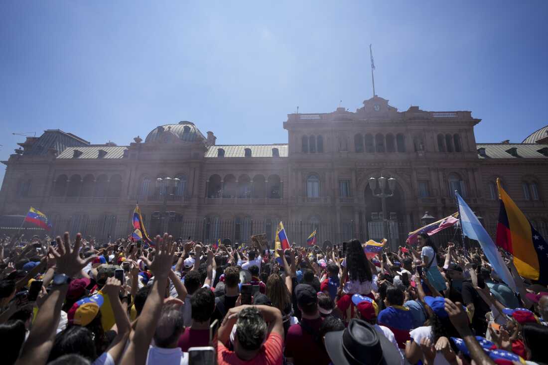 People watch Venezuela's opposition leader Edmundo Gonzalez Urrutia and Argentine President Javier Milei wave to supporters from the government house balcony in Buenos Aires, Argentina, Saturday, Jan. 4, 2025.