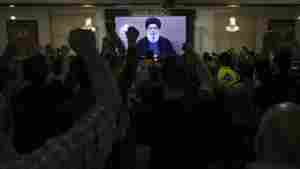 Hezbollah supporters raise their fists and cheer as they watch a speech given by Hezbollah leader Sayyed Hassan Nasrallah on a screen during a ceremony to commemorate the death of senior Hezbollah commander Taleb Sami Abdullah, 55, who was killed last week by an Israeli strike in south Lebanon, in the southern Beirut suburb of Dahiyeh, Lebanon, Wednesday, June 19, 2024. (AP Photo/Bilal Hussein)
