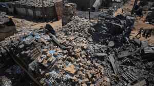 Palestinians walk past a food-aid warehouse damaged in an Israeli airstrike that targeted a nearby house in Deir al-Balah, central Gaza Strip, Wednesday, Aug. 26, 2026.