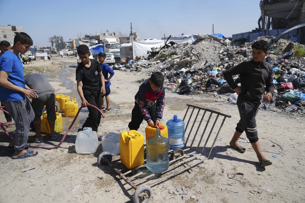Young Palestinians fill cans with water in Jabaliya, northern Gaza Strip, on Sunday. Arab negotiators are trying to broker a ceasefire deal that would avert a return to fighting in Gaza and begin serious negotiations toward a formal end of the war, since the breakdown of the Israel-Hamas ceasefire deal at the beginning of the month. (AP)
