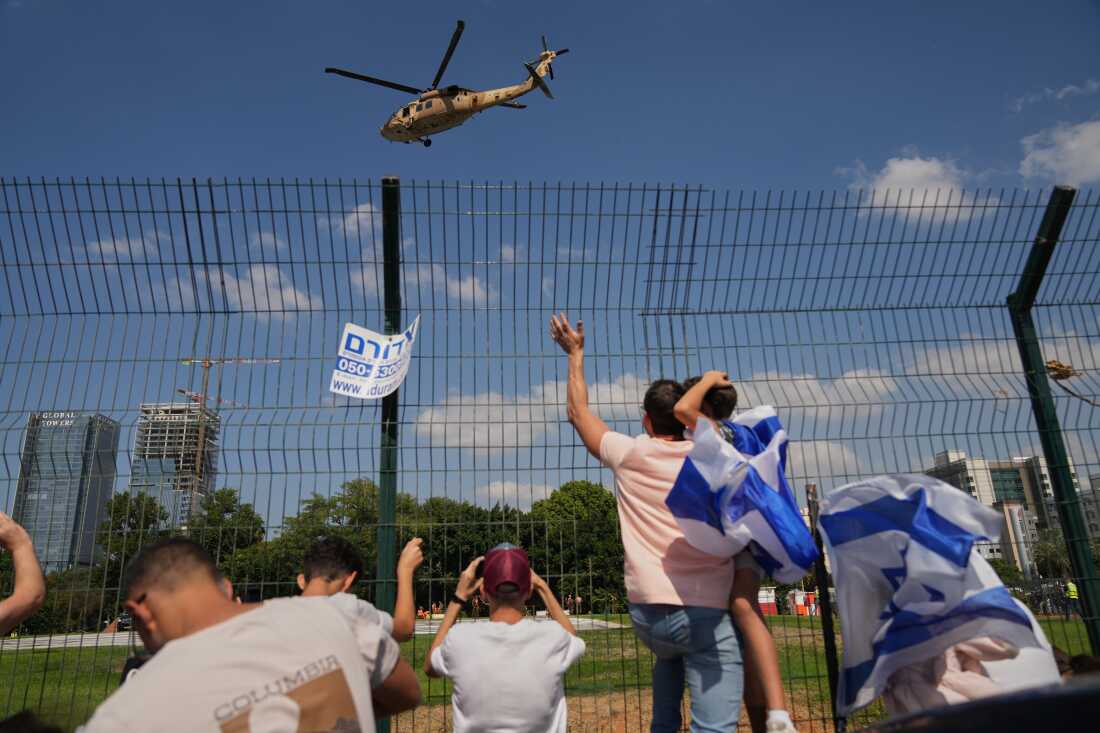 People watch a military helicopter carrying Israeli freed hostages arrives at Beilinson hospital in Petah Tikva, Israel, after they were released from Hamas captivity in the Gaza Strip, Monday, Oct. 13, 2025. (AP Photo/Francisco Seco)