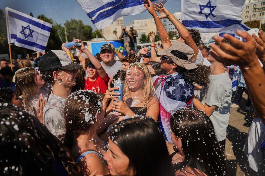People wave Israeli flags and spray foam in celebration after the arrival of freed hostages at Beilinson Hospital in Petah Tikva, Israel, following their release from Hamas captivity in the Gaza Strip, Monday, Oct. 13, 2025. (AP Photo/Francisco Seco)