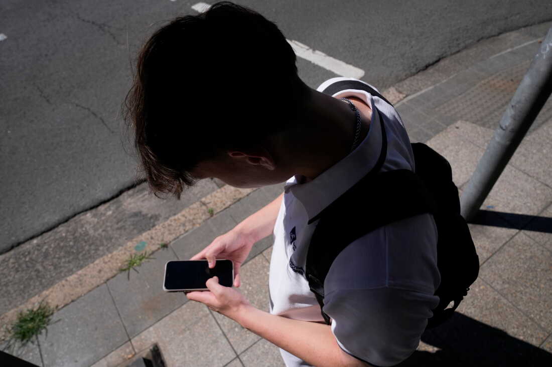 FILE - A teenage boy uses his phone in Sydney, Nov. 8, 2024.