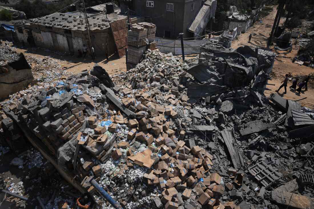 Palestinians walk past a food-aid warehouse damaged in an Israeli airstrike that targeted a nearby house in Deir al-Balah, central Gaza Strip, Wednesday, Aug. 26, 2026.