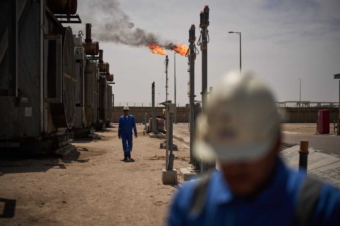 Workers walk in the Zubair oil field, whose operations have being reduced since the start of the Iran war, near Basra, Iraq, March 28.