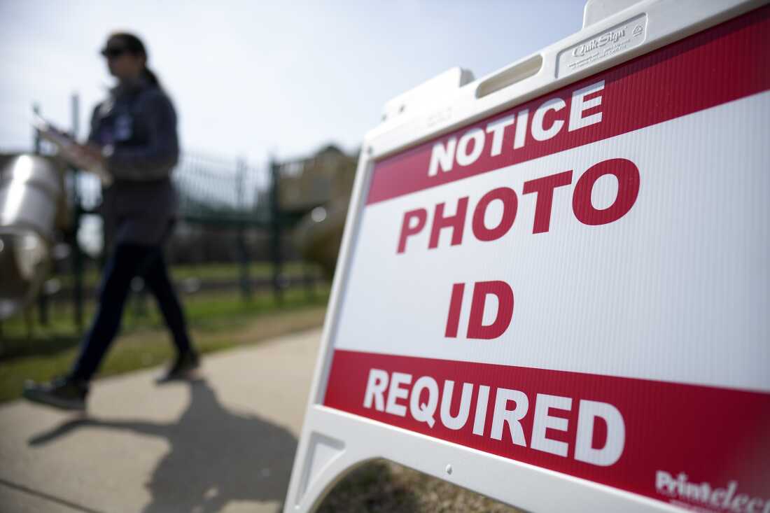 A voter walks past a sign requiring a photo ID at a polling location in Mount Holly, N.C., on March 5, 2024. North Carolina is one state deciding a voter ID ballot measure this year.