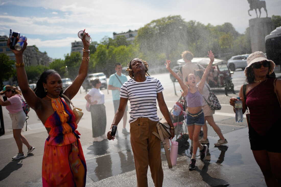 FILE - People cool off at a public water fountain In Paris, June 26, 2026.
