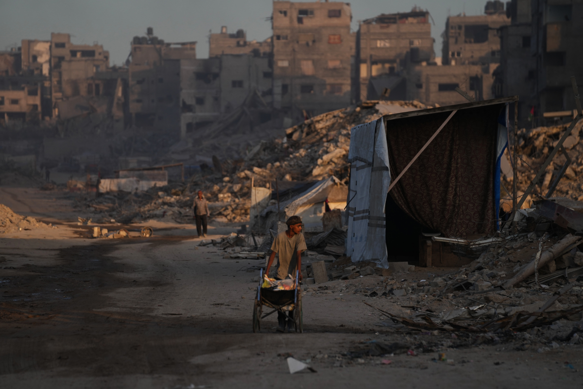Palestinians walk trough the destruction caused by the Israeli air and ground offensive in Sheikh Radwan neighborhood in Gaza City, Wednesday.
