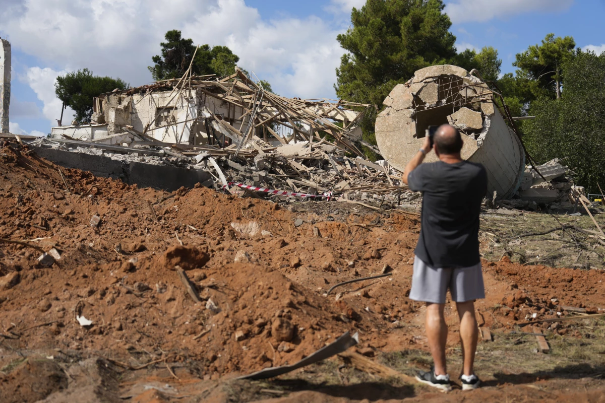 A man takes photos of a destroyed building that was hit in Iran's missile attack in Hod Hasharon, Israel, Wednesday, Oct. 2, 2024. (AP Photo/Ariel Schalit)