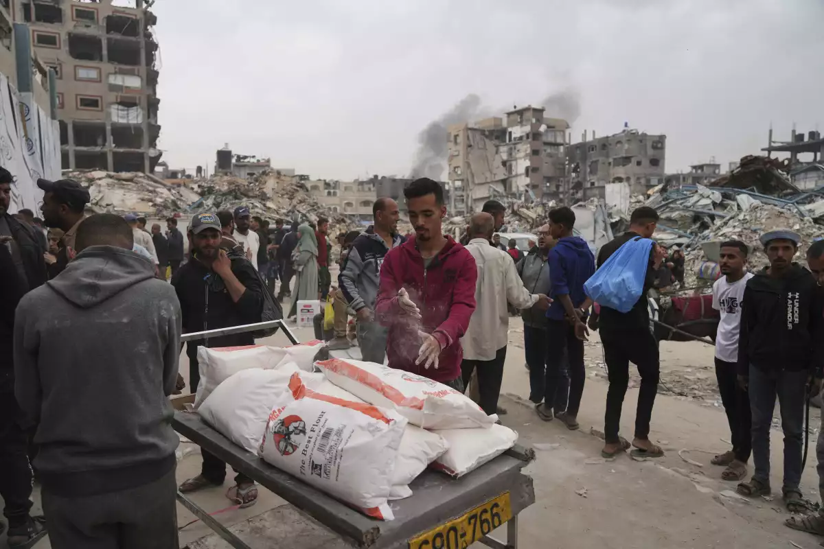Palestinians receive bags of flour and other humanitarian aid distributed by UNRWA, the U.N. agency helping Palestinian refugees in Jabaliya, Gaza Strip on Tuesday, April 1, 2025.