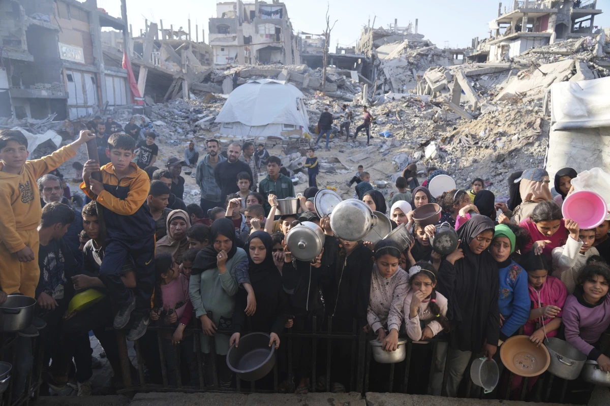 Palestinians wait for donated food at a distribution center in Beit Lahiya, northern Gaza Strip, Sunday, March 16, 2025.