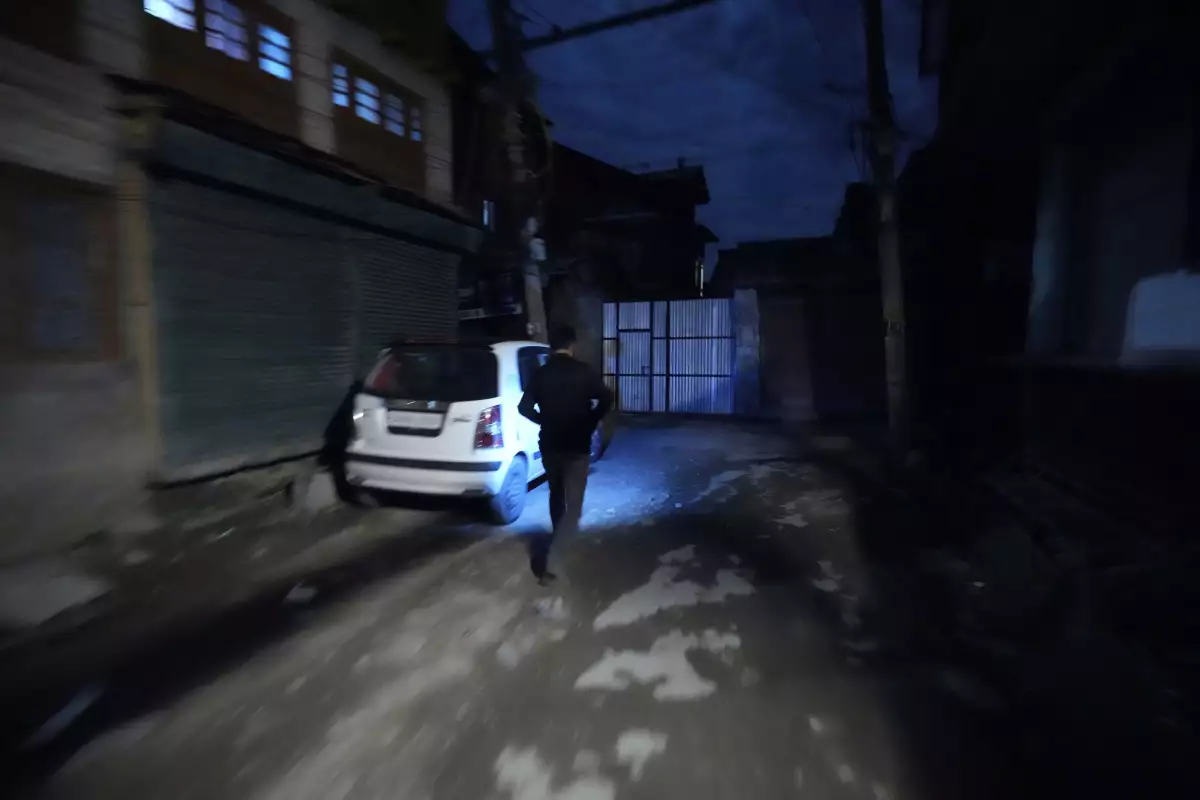 A Kashmiri man using a cellphone light during a blackout is seen after residents of the city of Jammu reported hearing explosions and sirens in Srinagar, Indian-controlled Kashmir, Thursday.
