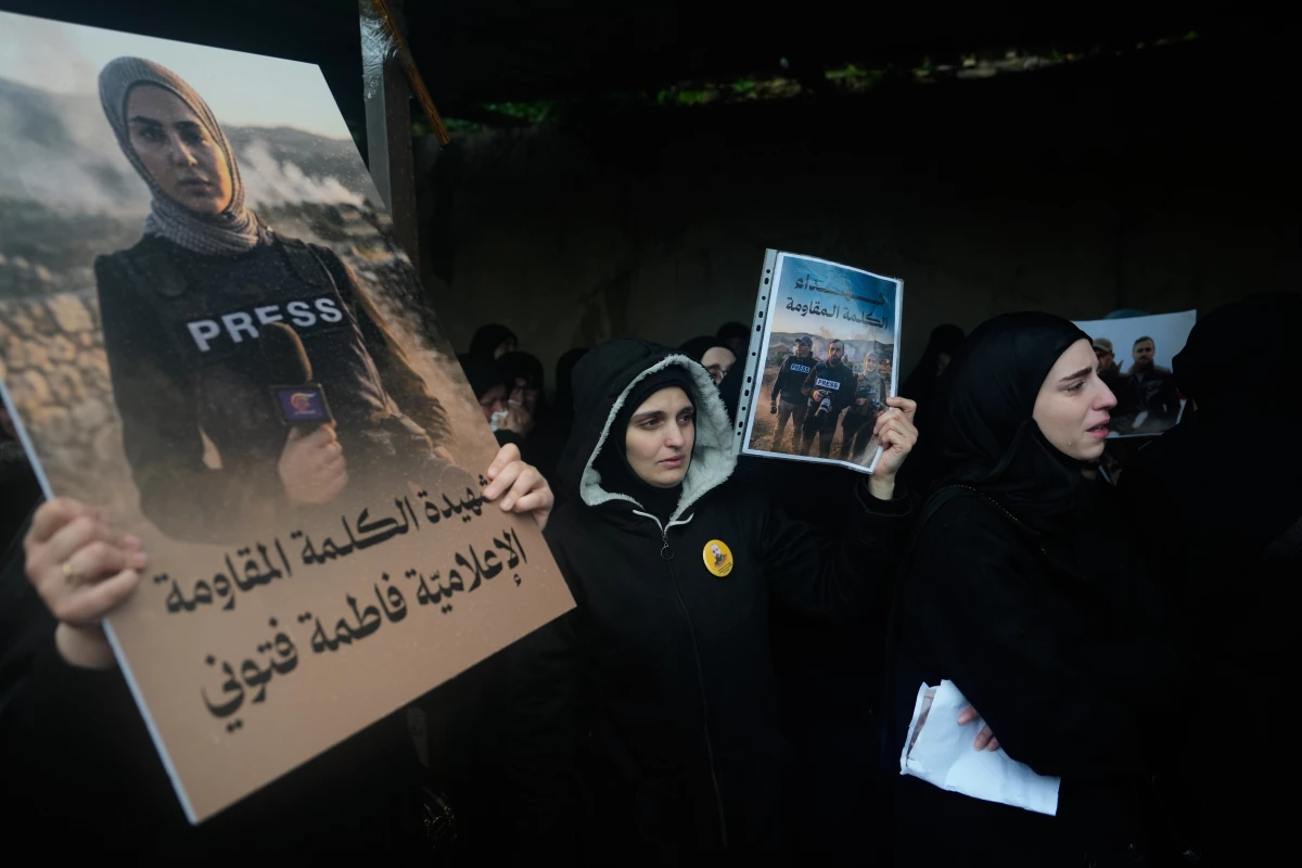 Women hold posters showing Al-Mayadeen TV reporter Fatima Ftouni, left, and, in another poster, Hezbollah's Al-Manar TV correspondent Ali Shoeib, center, and cameraman Ali Ftouni during their funeral at a temporary cemetery in Dahiyeh, Beirut's southern suburbs, Beirut, Lebanon, Sunday, March 29, 2026.