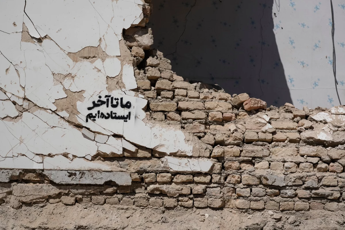 A residential building damaged by recent U.S.-Israeli strikes is seen with a sign on its wall that reads in Farsi: 'We stand till the end,' in Fardis, west of Tehran, Iran, Friday, April 3, 2026.