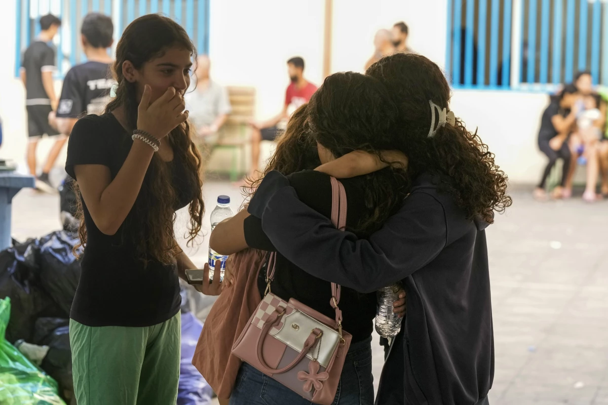 Displaced youth hug as they take shelter at a school in Beirut, after fleeing the Israeli airstrikes in the south with their families on Thursday