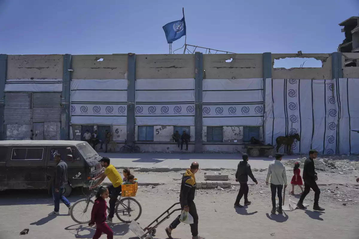 Palestinians walk next to the closed humanitarian aid distribution center of UNRWA, the U.N. agency helping Palestinian refugees in Jabaliya, Gaza Strip on Tuesday, April 29, 2025.