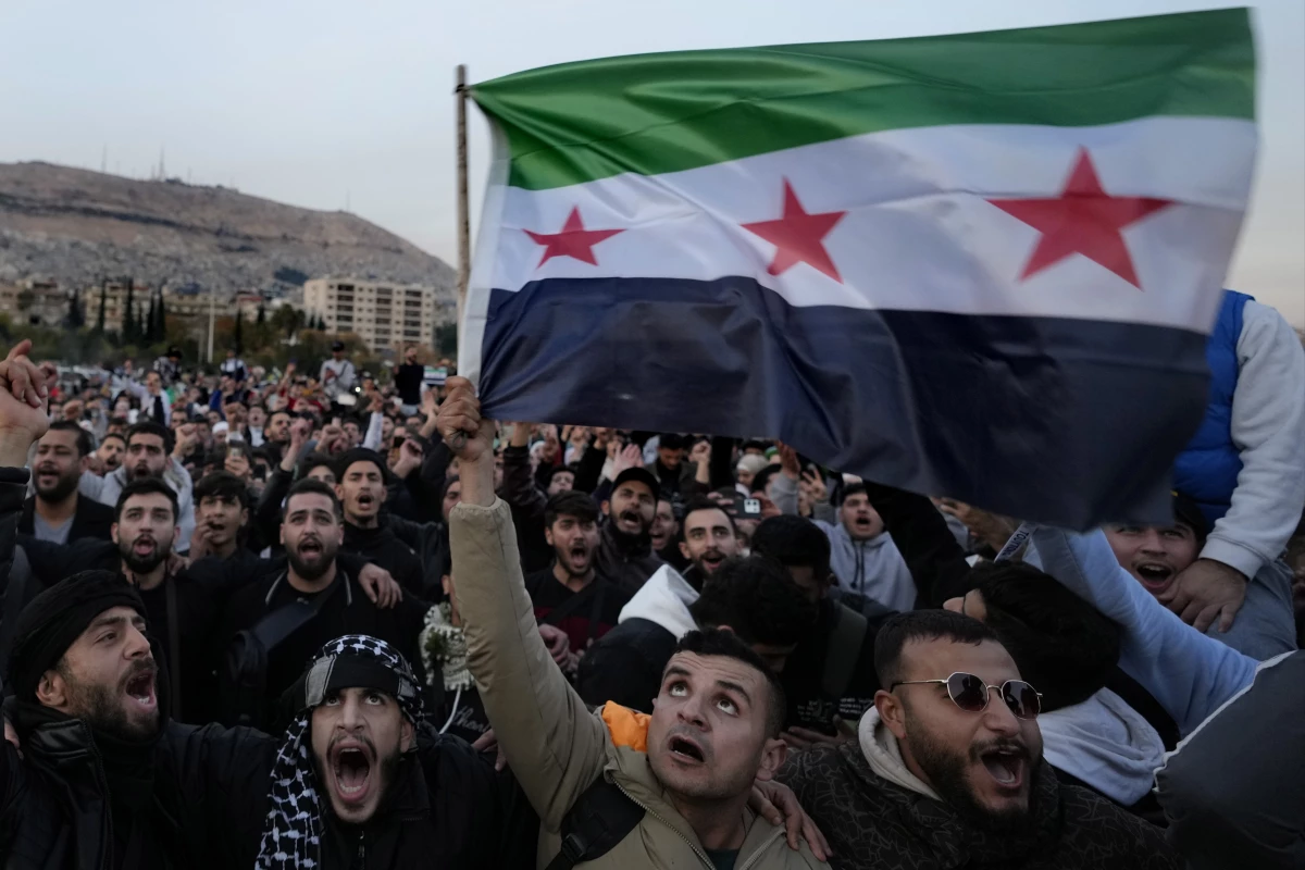 Syrian citizens wave the revolutionary flag and shout slogans, as they celebrate during the second day of the take over of the city by the insurgents in Damascus on Monday.