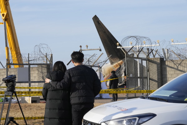 Mourners watch the site of a plane fire from outside of Muan International Airport in Muan, South Korea.The cause of the crash is still under investigation.