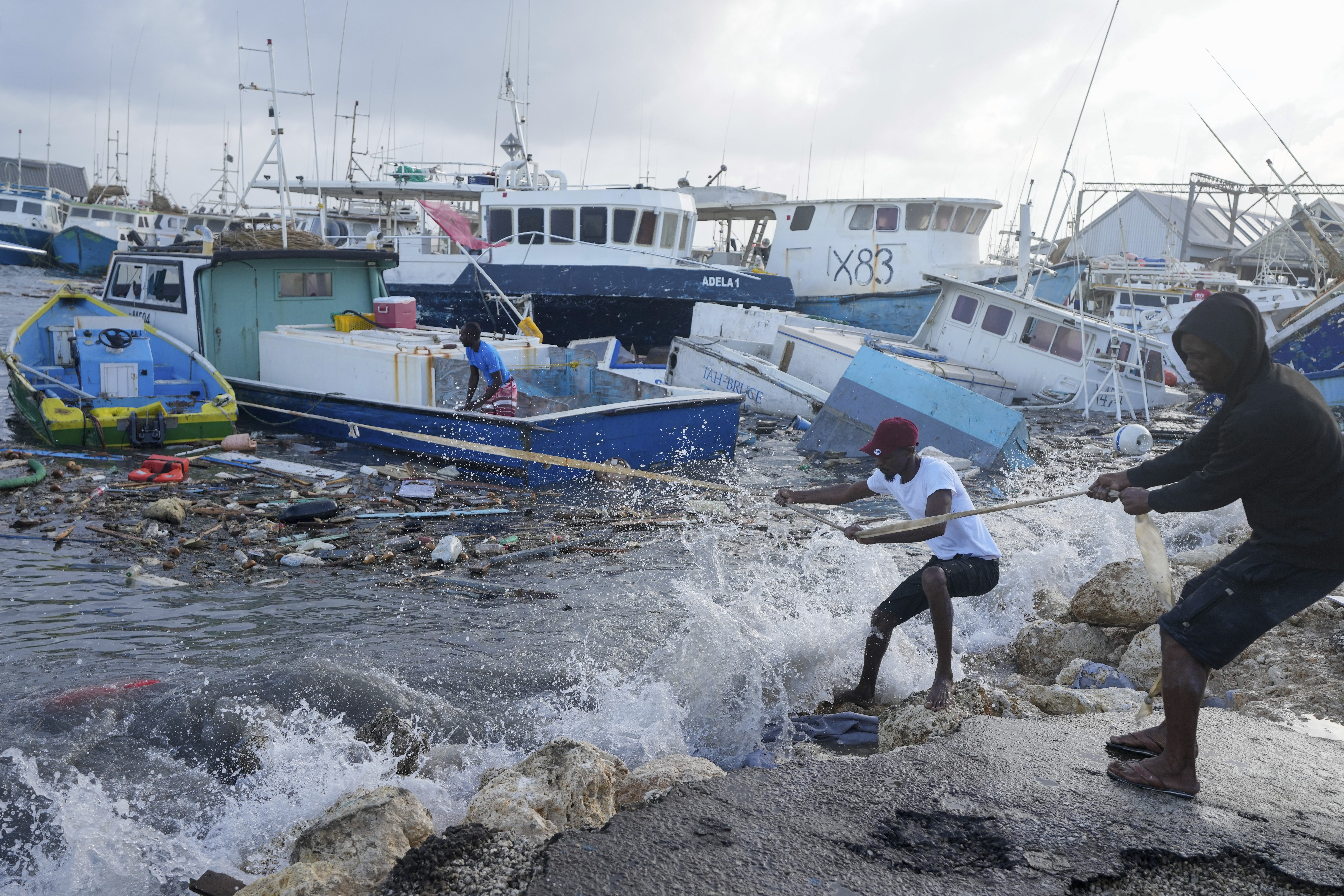 Fishermen pull a boat damaged by Hurricane Beryl back to the dock at the Bridgetown Fisheries in Barbados on Monday.  (AP)