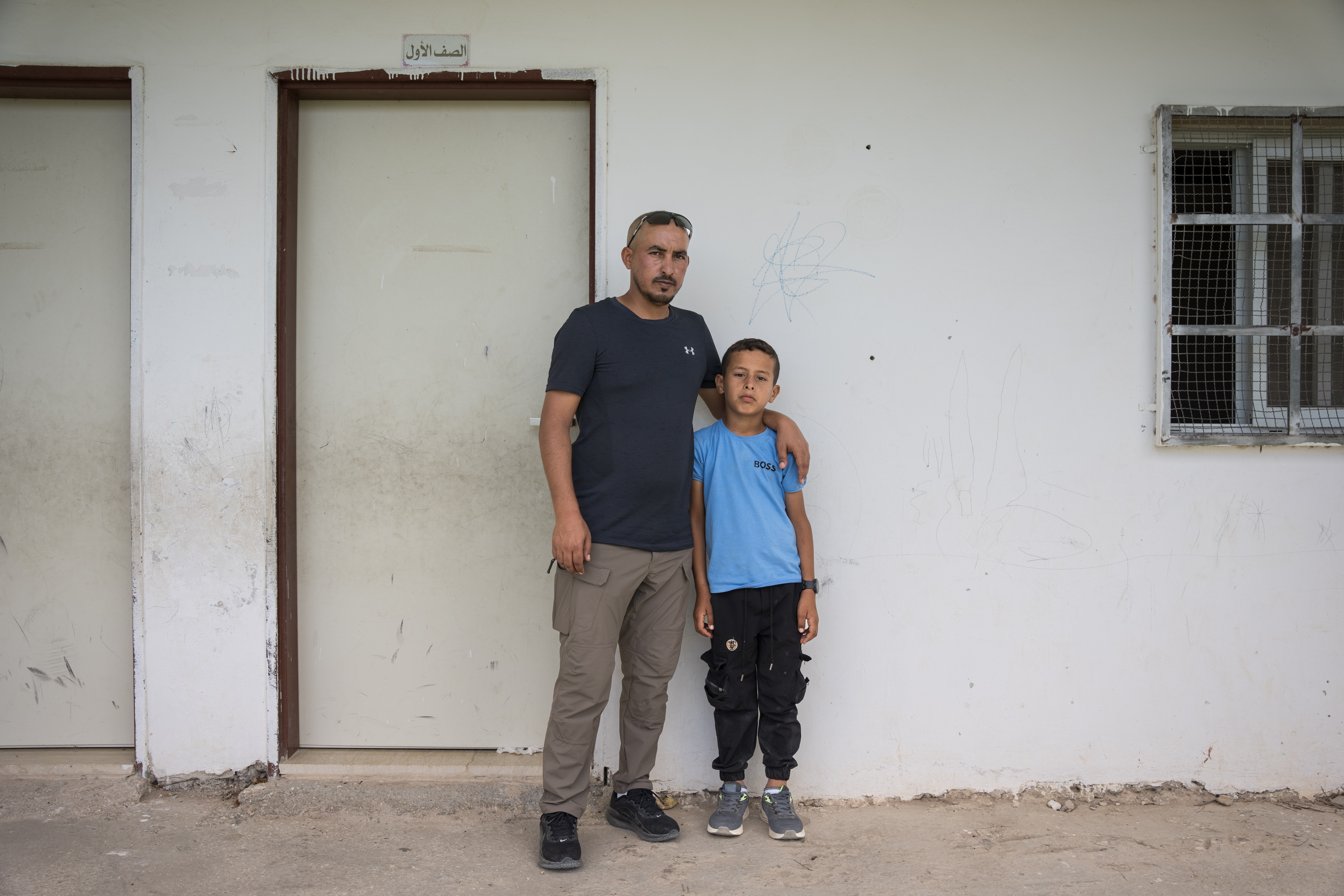 Suliman Mleihat, 32, and his nine-year-old son Obeida stand in front of Obeida's classroom, where he sheltered from settlers who attacked the school in the Mu’arrajat Bedouin community in mid-September.