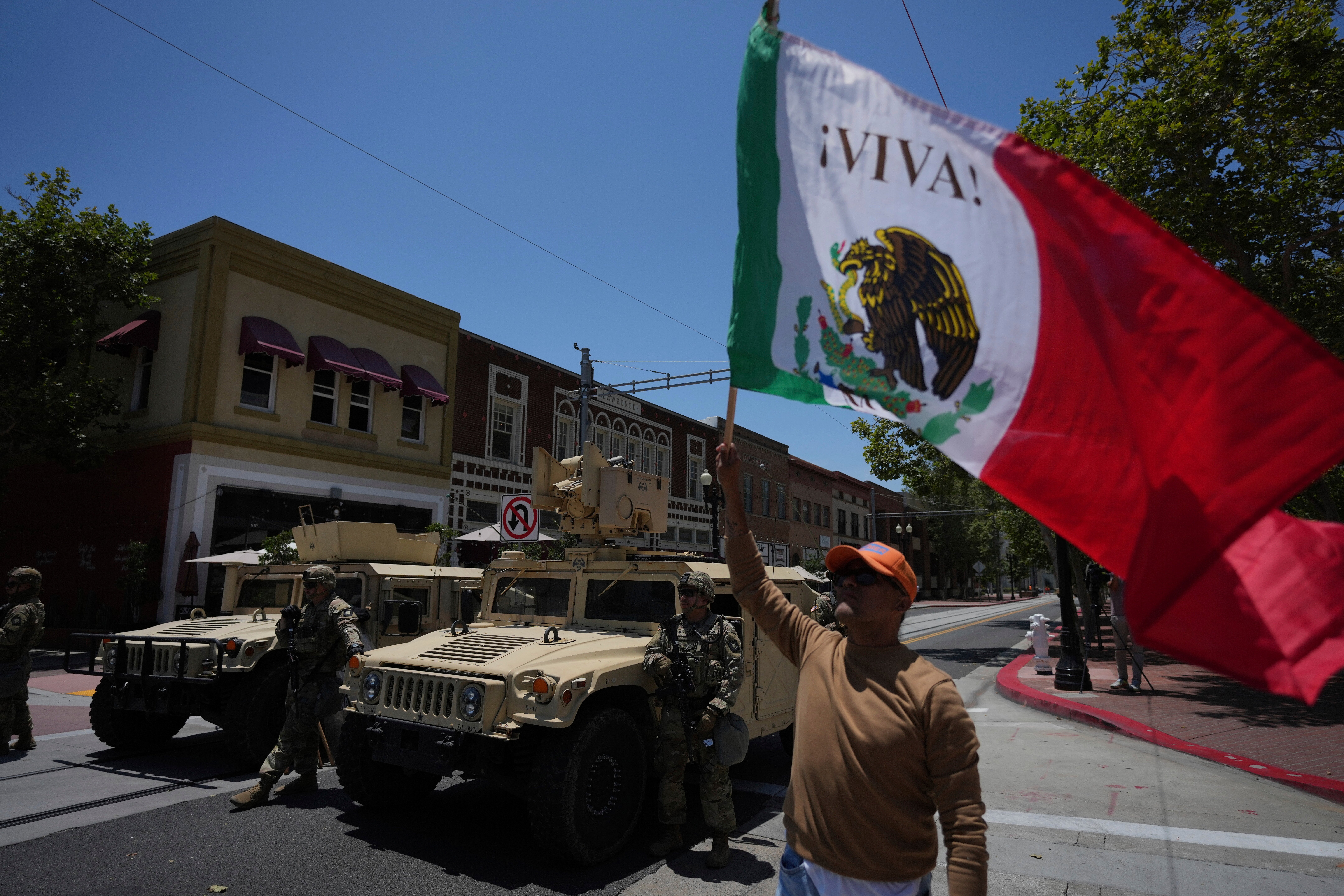 A protester waves a flag standing by California National Guard parked along a street in Santa Ana, Calif. on Tuesday, June 10, 2025. (AP)