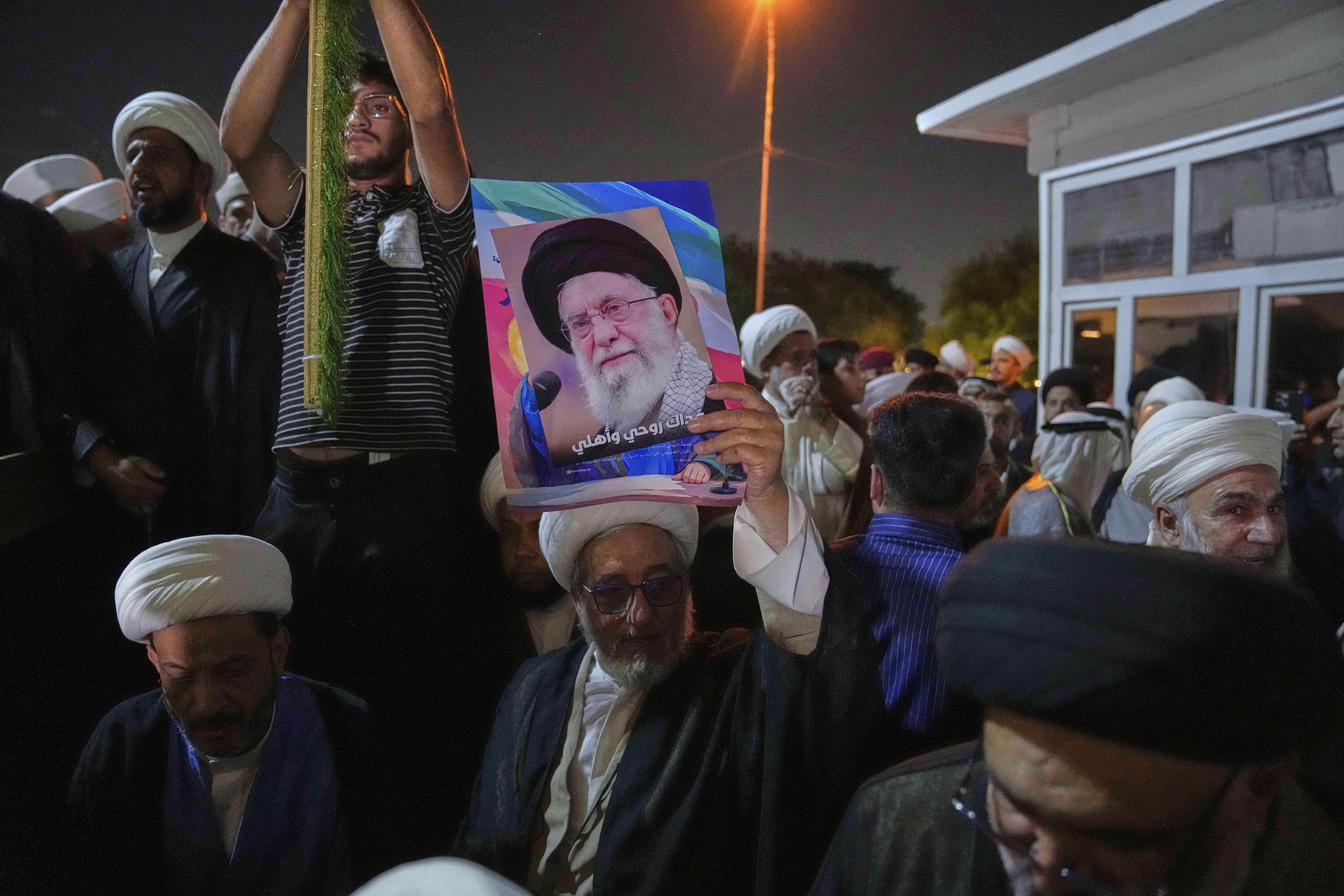 An Iraqi Shiite cleric holds a portrait of Iran