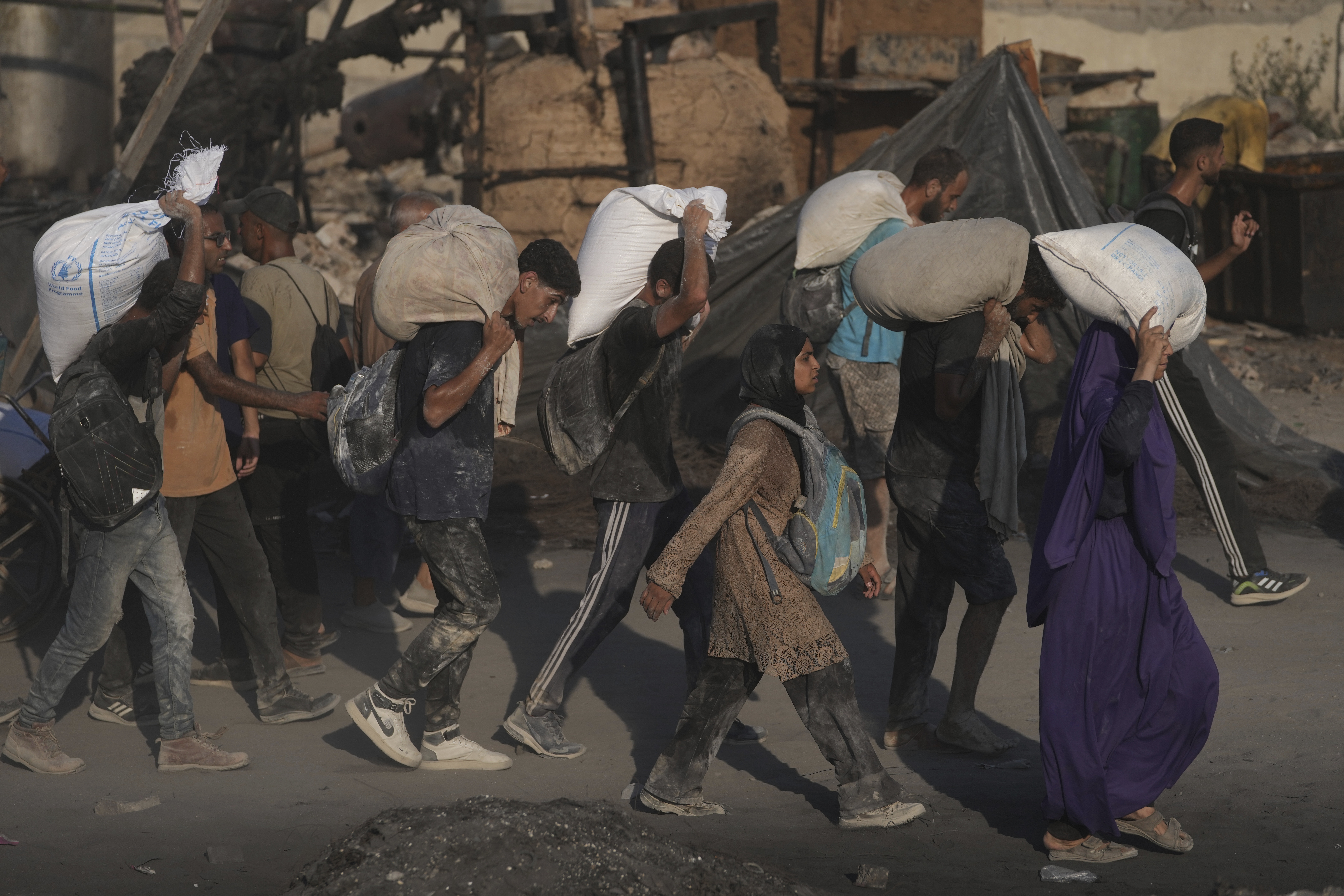 Palestinians carry sacks of flour unloaded from a humanitarian aid convoy that reached Gaza City from the northern Gaza Strip on Saturday, July 26, 2025.