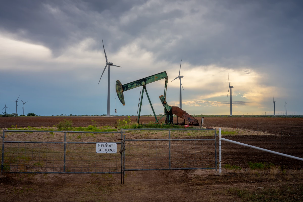 An oil pumpjack is seen near a field of wind turbines in Nolan, Texas.