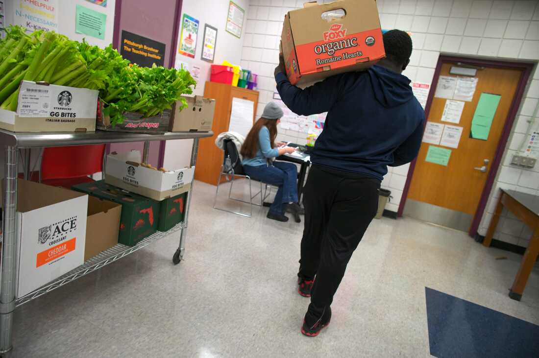 A student leaves the food pantry at Brashear High School in Pittsburgh with a box of goods. 