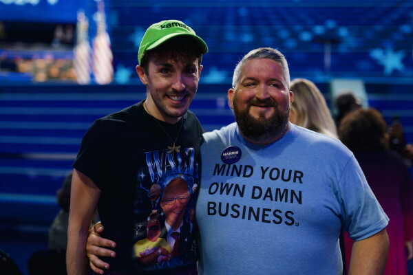 Adam Peters (left) and C.J. Petersen (right), both delegates from Iowa, wore t-shirts in homage to Minnesota Gov. Tim Walz leading up to his speech on the third night of the DNC. Grace Widyatmadja/NPR
