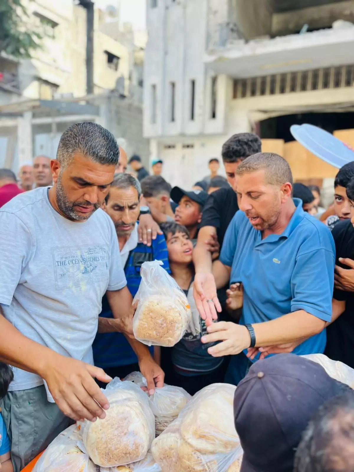Volunteers Naeem Salem, Nabeel Nassar, and Motaz Ziyada, (from left to right), stand at the food kitchen and help pass out bread to people in north Gaza.