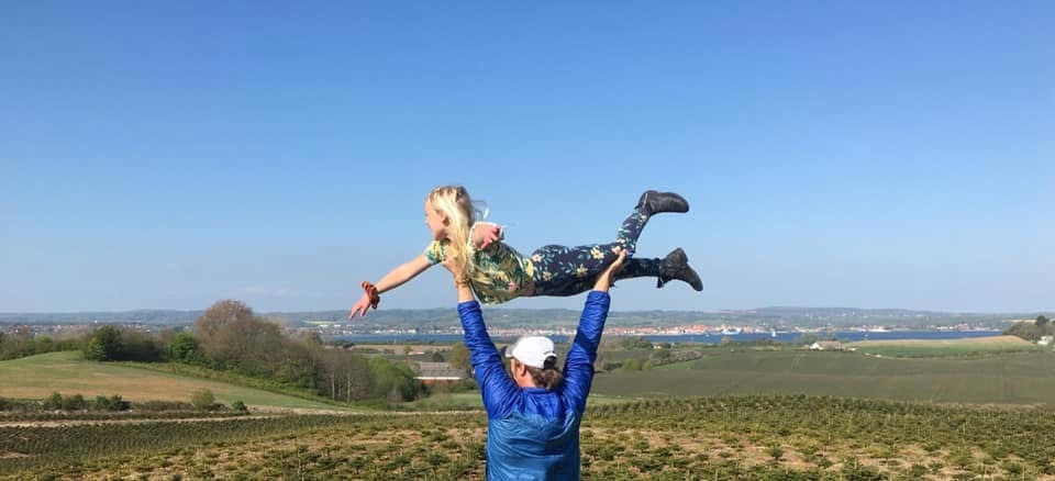 John lifts his young daughter above his head so she looks like she