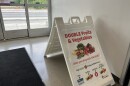 An A-frame sign, explaining SNAP and Produce Perks stands in the entrance to Gem City Market