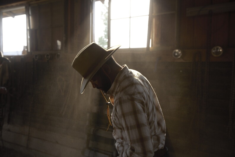 Baratunde Thurston stands in the sunlight in an Idaho barn during his horseback riding trip.