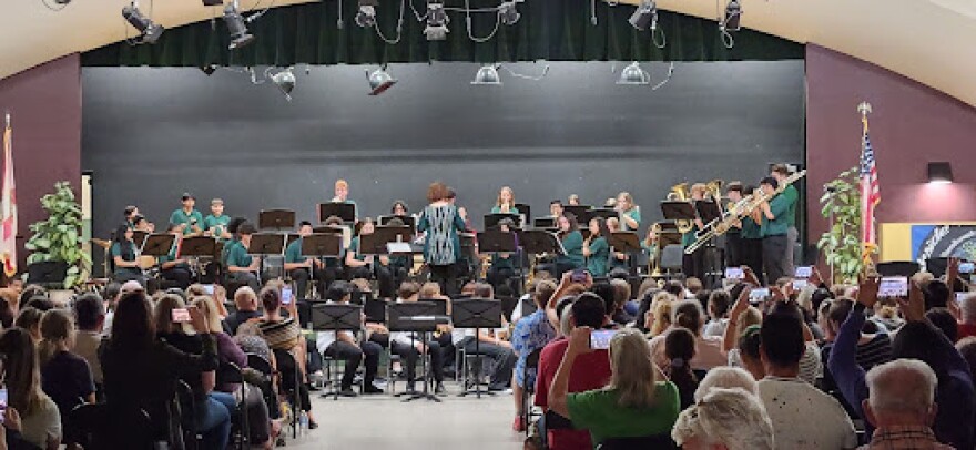 An orchestra in the distance with people sitting in the foreground