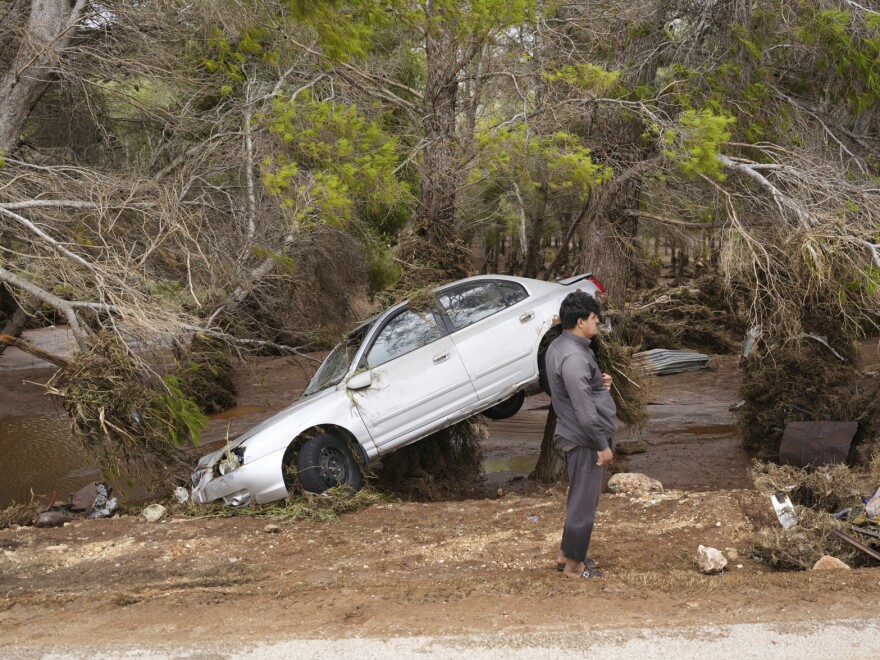 In this photo provided by the Libyan government, a car sits partly suspended in trees after being carried by floodwaters in Derna, Libya, on Monday, Sept. 11, 2023.