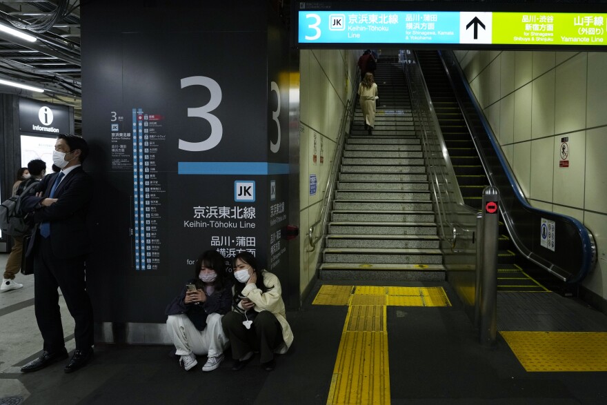 People wait for a train service to resume at a Tokyo train station in Tokyo, early Thursday, March 17, 2022, as all the services were suspended after an earthquake hit the area. A powerful 7.3 magnitude earthquake has struck off the coast of Fukushima in northern Japan, triggering a tsunami advisory and plunging more than 2 million homes in the Tokyo area into darkness. (AP Photo/Hiro Komae)