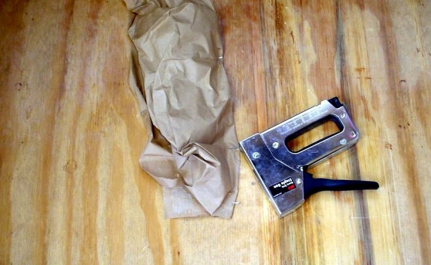 A staple gun was used to attach a brown paper bag to the board. 