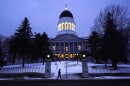 A pedestrian walks by the Maine State House, Wednesday, Jan. 13, 2021, in Augusta, Maine.