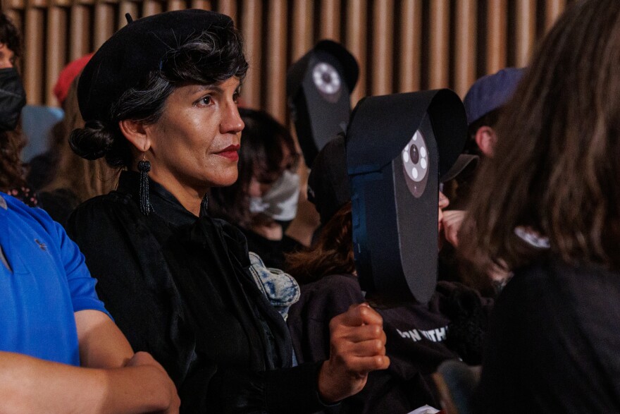 Privacy advocates hold signs meant to resemble Flock Safety cameras during a Lansing City Council meeting on Aug. 24, 2026.