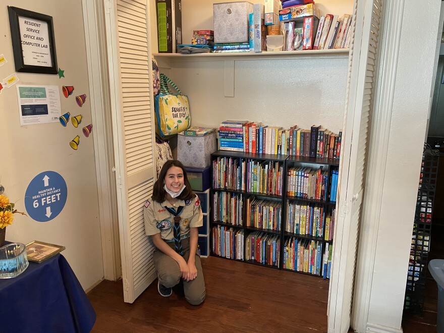 Madison Knefley sits in front of her finished eagle project: a library in the community room at a Lake Highlands public housing complex. 