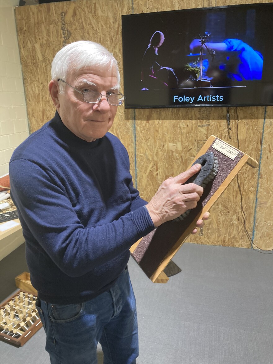 Jack Dominic makes train sounds by rubbing a scrub brush on coarse sandpaper.