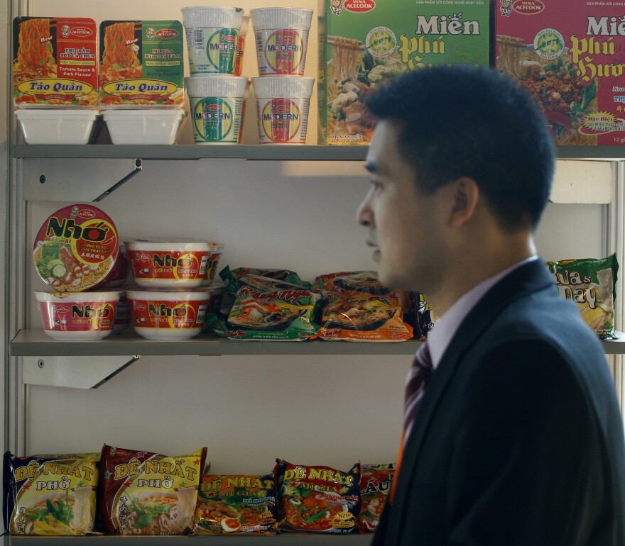 FILE - A man walks past packages of instant noodles manufactured by Acecook Vietnam on display at the 7th World Instant Noodle Summit in Kuala Lumpur, Malaysia, Wednesday, April 21, 2010. (AP Photo/Lai Seng Sin)