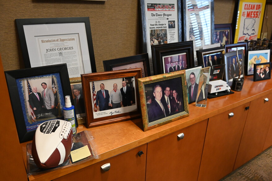 Photos on Georges’ office credenza include images of him with President George W. Bush, for whom Georges served as a prominent fundraiser and supporter, reflecting his legacy as an independent politico who moved from Republican to Democrat in identity with strong ties in both parties.