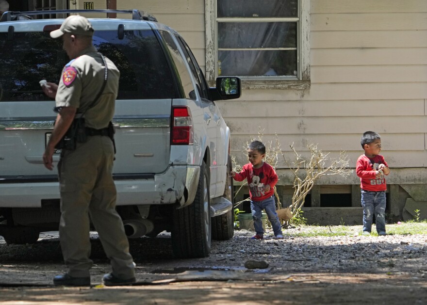 Josue, left, and Nathan Barcenas play outside their home Sunday as authorities continue to investigate the neighborhood where the deadly shooting took place.