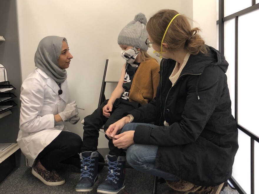 Pharmacist Marwa Bakr talks to 5-year-old Albar Pajari after administering his COVID vaccination.