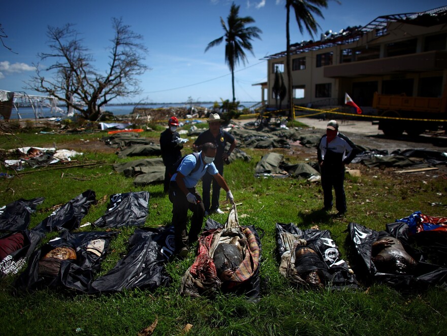 Filipino coroners examine the rotting remains of bodies left at a makeshift morgue outside Tacloban's City Hall.