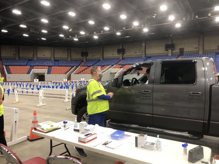 A worker at Broadbent Arena talks with a patient in a drive-through COVID-19 vaccination line before. 