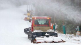Tucker County, West Virginia, USA - January 18, 2022: A snowcat grooms a slope at Blackwater Falls State Park as a snow-making cannon blasts new “snow” onto the hill.