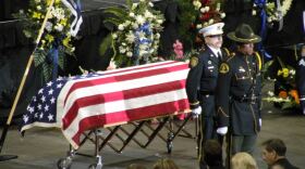 An honor guard stands before the flag-draped casket bearing the body of Corrections Officer Jayme Lee Biendl during a memorial service held Tuesday at Comcast Arena in Everett. Biendl's family sits in the front row.
